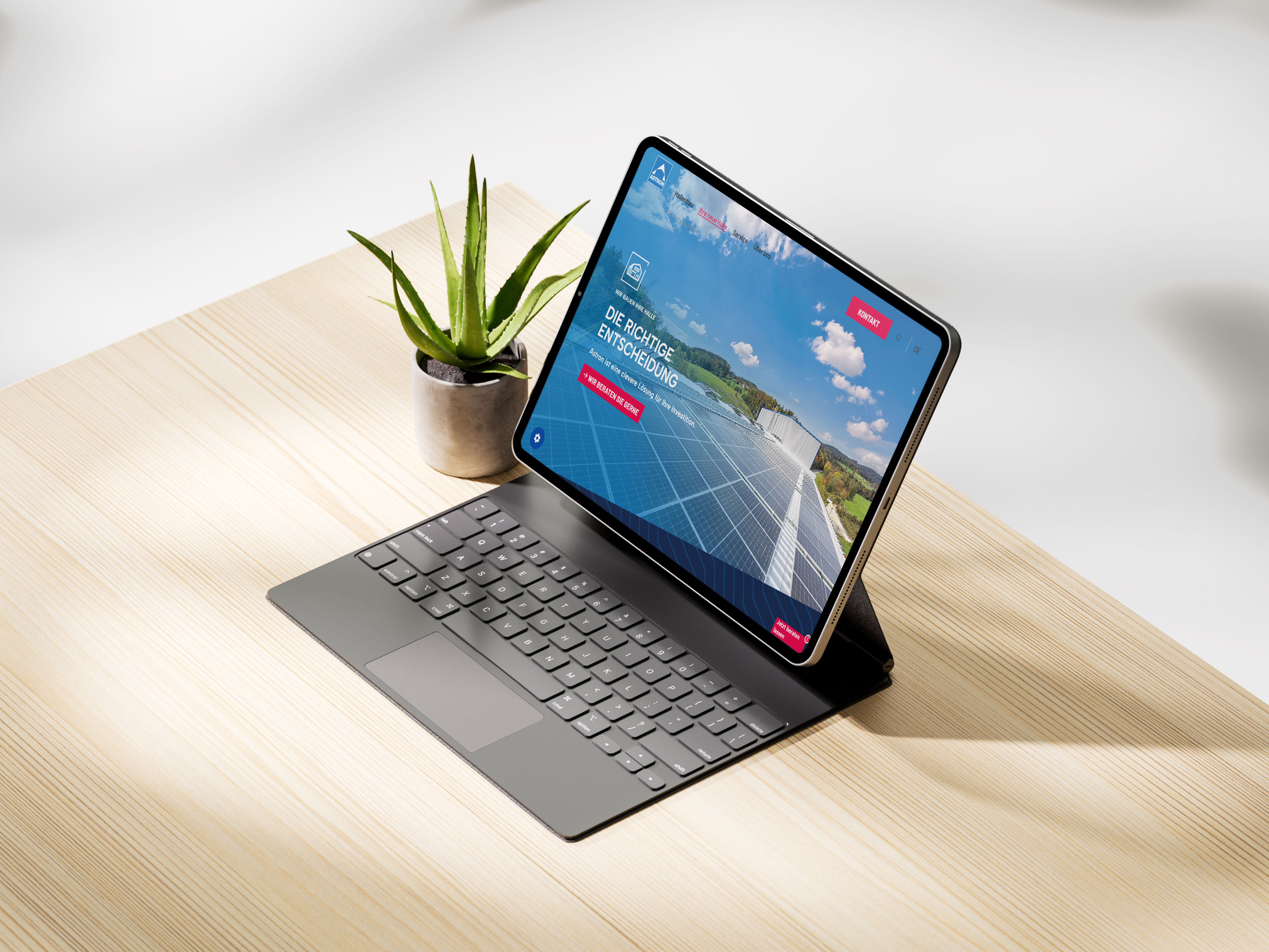 Mockup der Seite in einem Tablet mit Tastatur neben einer kleinen Topfpflanze