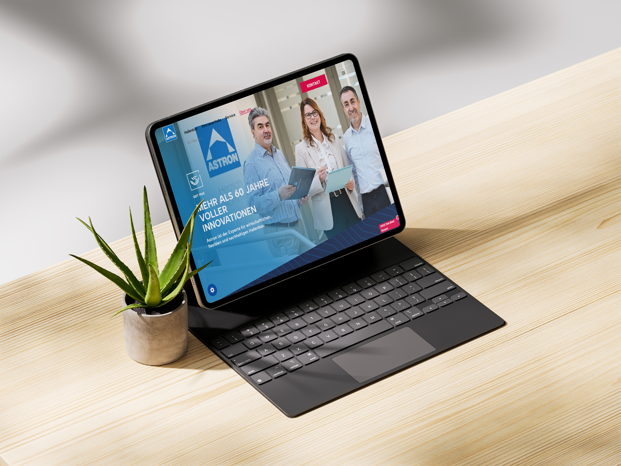 Mockup der Seite in einem Tablet mit Tastatur neben einer kleinen Topfpflanze