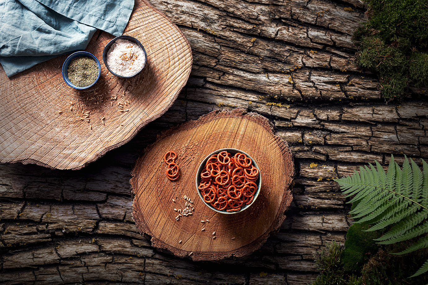 Foto von der Draufsicht auf eine Schale Bio-Dinkel-Mini-Brezeln auf einer Holzscheibe. Der Untergrund ist eine grobe Rindenstruktur.
