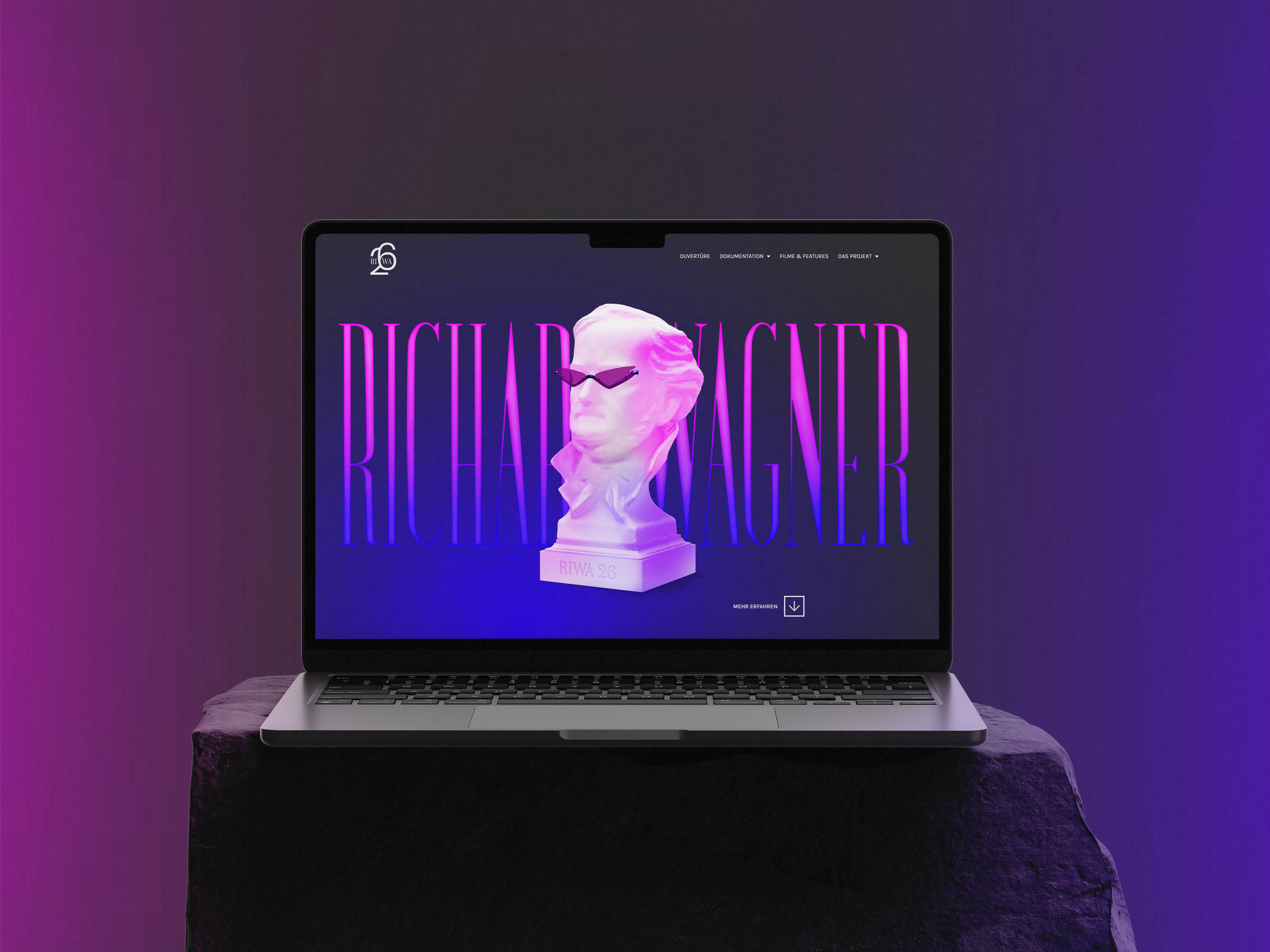Laptopbildschirm zeigt die Startseite der RIWA26 Website mit dem zentralen Visual der Büste von Richard Wagner mit Sonnenbrille.