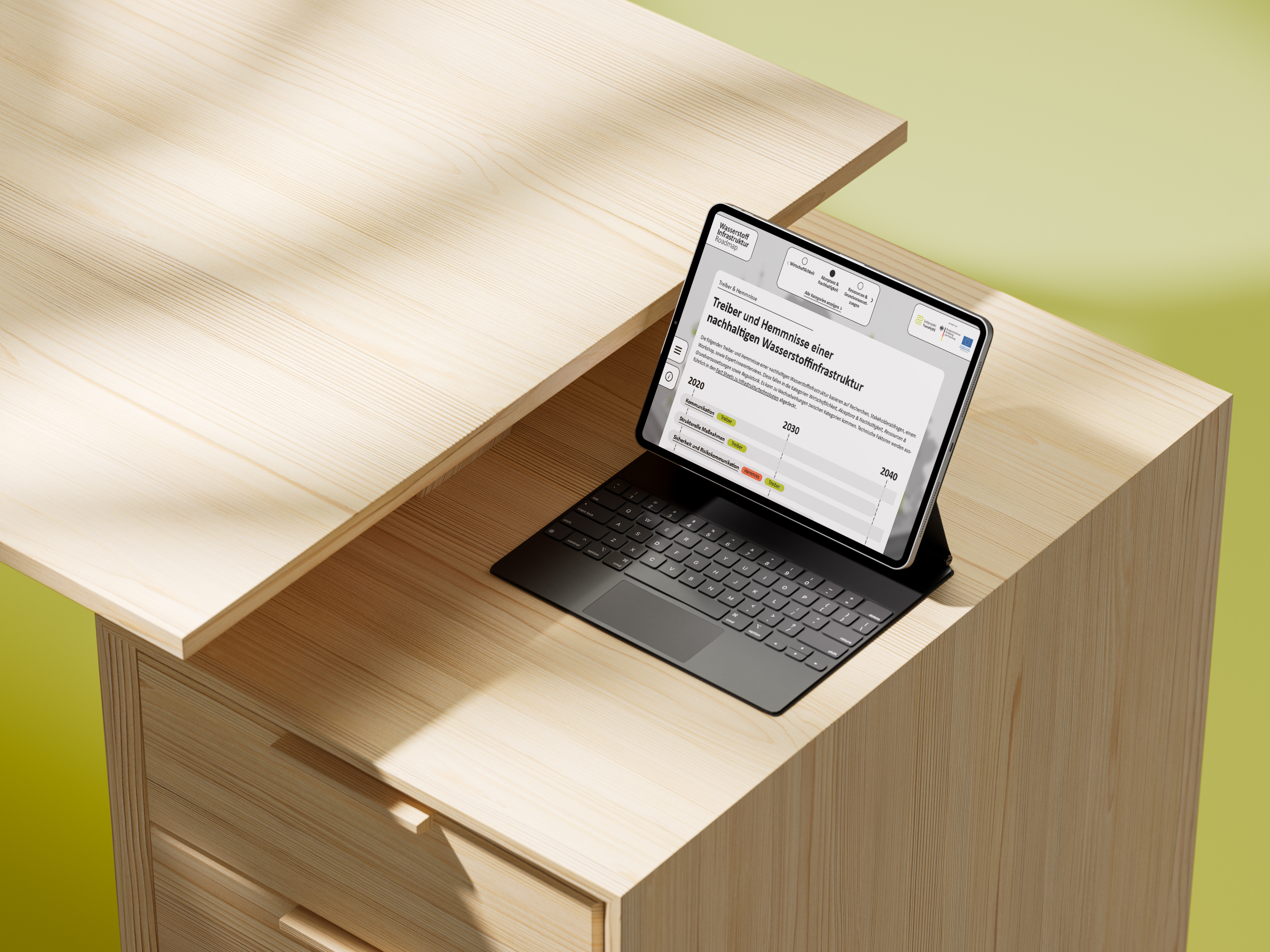 Tablet mit Tastatur auf einem Schreibtisch aus Kiefernholz, auf dem Bildschirm eine grafische Übersicht zu Treibern und Hemmnissen der Entwicklung der Wasserstoff-Infrastruktur.