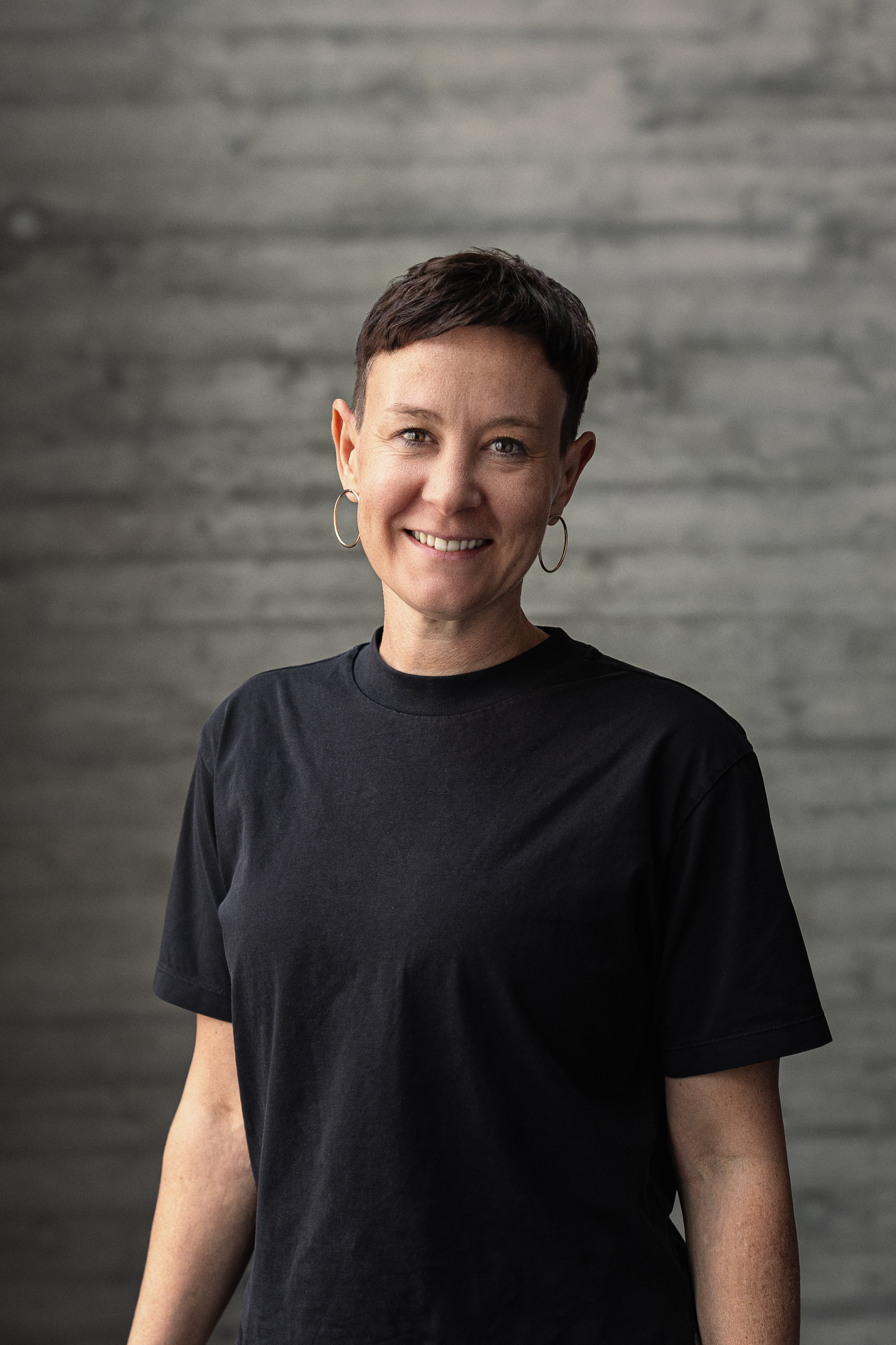 Portrait von Katharina, Teamlead Social, vor einer grauen Sichtbetonwand