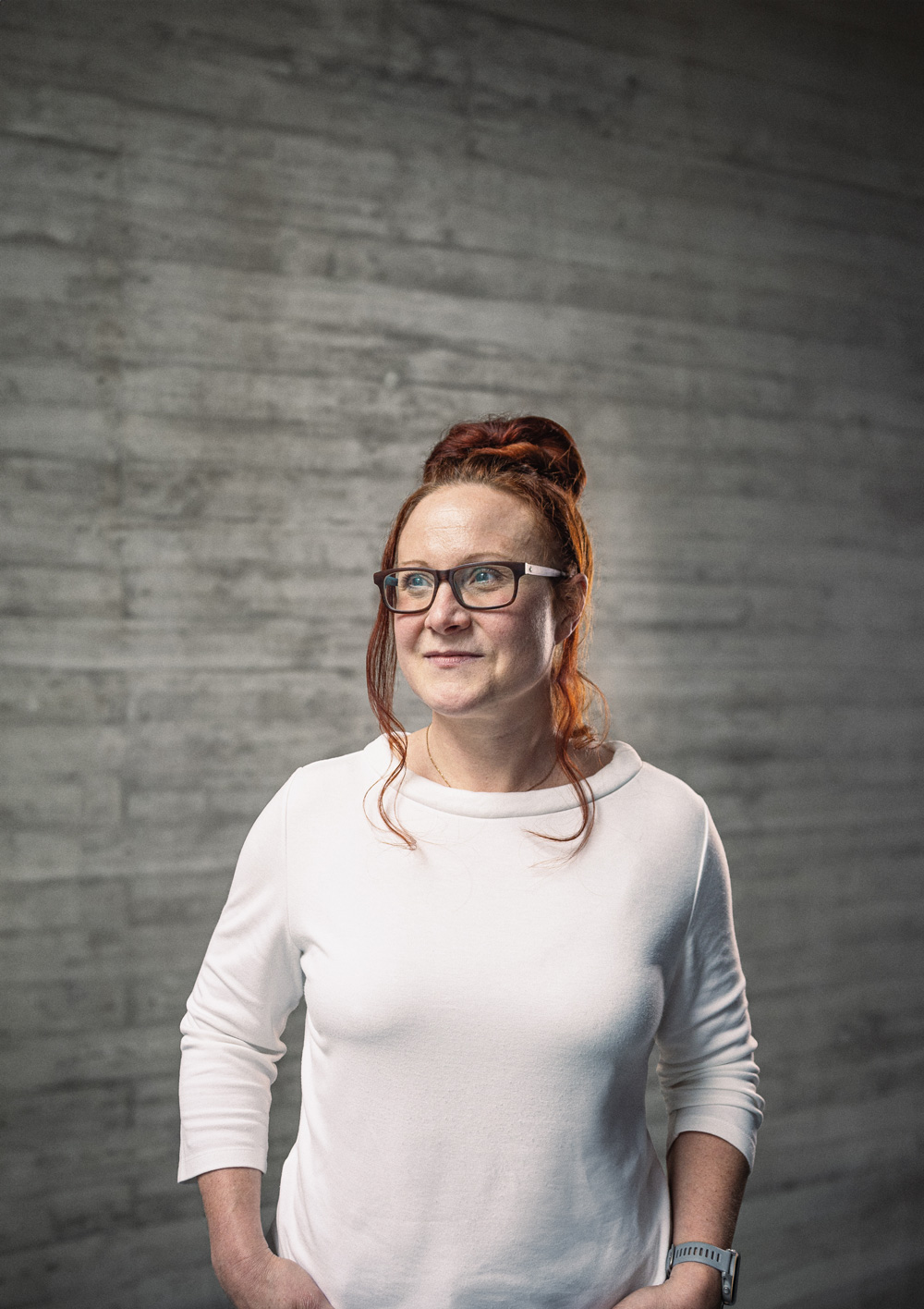 Portrait von Katharina, Teamlead Projektmanagement vor einer grauen Sichtbetonwand
