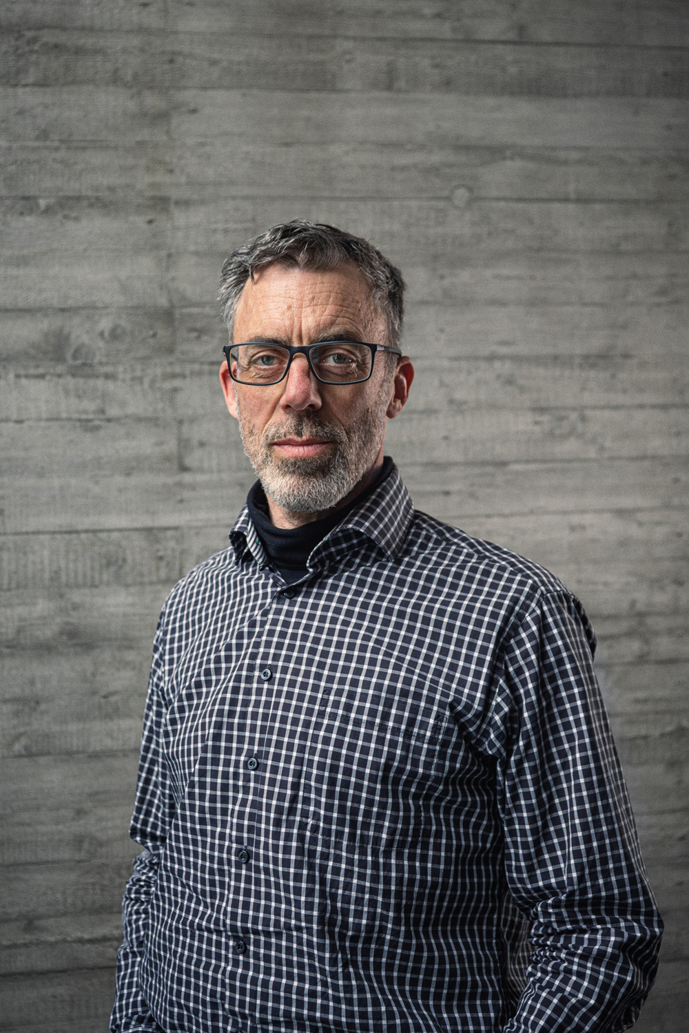 Portrait von Uwe Raabe, Geschäftsführer Technik, vor einer grauen Sichtbetonwand